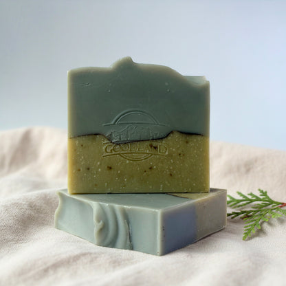 Two green soap bars with Goodland brand logo on a light fabric background