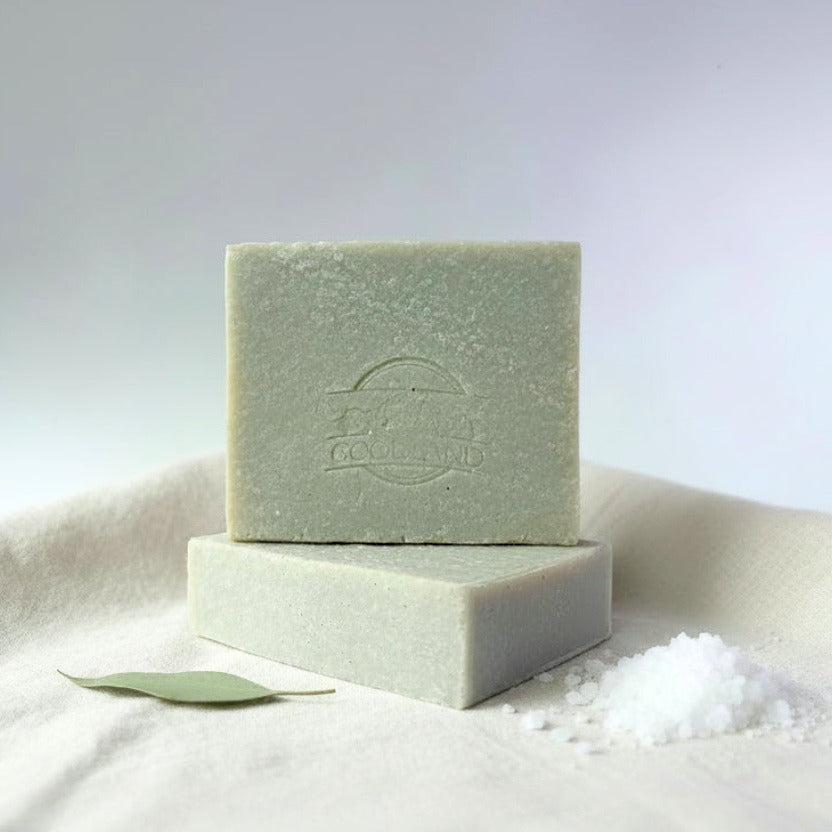 Two green bars of soap on a white surface with a light gray background